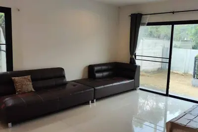 a black leather couch in a living room with a window at Baan Salaya in Salaya