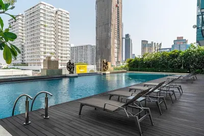 a swimming pool with lounge chairs on a building at Thonglor area 1 Bedroom FastWiFi Sauna Big Swimming Pool 38 in Bangkok
