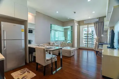 a kitchen and living room with a table and a refrigerator at Thonglor area 1 Bedroom FastWiFi Sauna Big Swimming Pool 38 in Bangkok