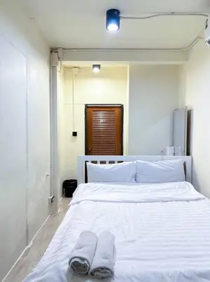 a white bed with two pairs of slippers on it at Chubbi5 room11 in Bangkok