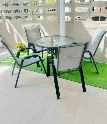 a glass table and chairs on a floor with grass at 93 House in Ban Zong Katiam