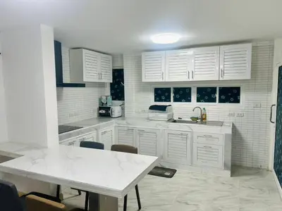 a kitchen with white cabinets and a white table at 93 House in Ban Zong Katiam