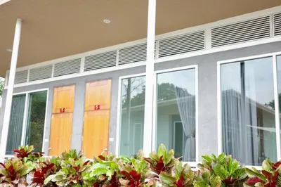 a house with glass doors and flowers in front of it at Woodview Resort in Samut Prakan