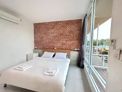 a bedroom with two beds and a brick wall at Woodview Resort in Samut Prakan