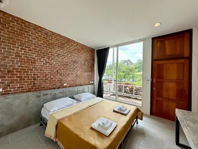 a bedroom with a bed and a brick wall at Woodview Resort in Samut Prakan