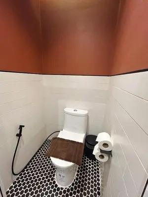 a bathroom with a toilet with a black and white tile floor at Brix26 in Bangkok