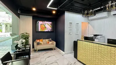 a lobby with a couch and a tv on the wall at Skye Hotel Bangkok in Bangkok