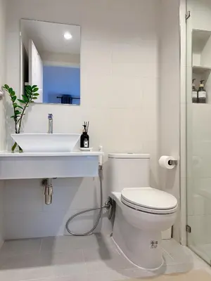 a white bathroom with a sink and a toilet at Komfy Quarters in Sathani Bang Khen