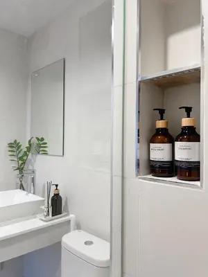a bathroom with three bottles of whiskey on a shelf at Komfy Quarters in Sathani Bang Khen