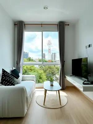 a living room with a white couch and a large window at Komfy Quarters in Sathani Bang Khen