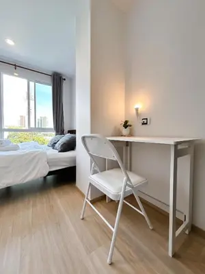 a bedroom with a desk and a bed and a chair at Komfy Quarters in Sathani Bang Khen