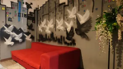 a red couch against a wall with birds on it at 89 Bed & Studio Hostel in Godown