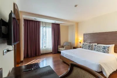 a hotel room with a bed and a television at Journeyhub Sukhumvit 26, Bangkok - Formerly St James Hotel in Bangkok