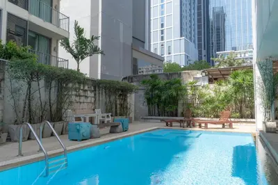 a large blue swimming pool with buildings in the background at Journeyhub Sukhumvit 26, Bangkok - Formerly St James Hotel in Bangkok