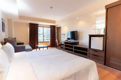 a hotel room with a large bed and a television at Journeyhub Sukhumvit 26, Bangkok - Formerly St James Hotel in Bangkok