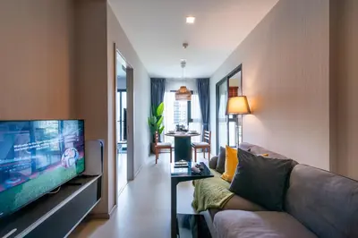 a living room with a couch and a flat screen tv at Luxurious Apartment with Train Access in Bangkok