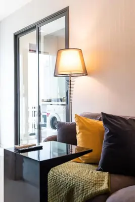 a living room with a couch and a table with a lamp at Luxurious Apartment with Train Access in Bangkok