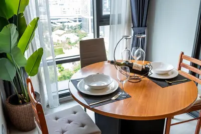 a wooden table with plates and glasses on it at Luxurious Apartment with Train Access in Bangkok
