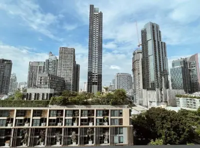 a building in front of a city with tall buildings at Luxurious Apartment with Train Access in Bangkok