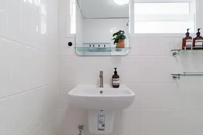 a white bathroom with a sink and a window at Huai Khwang Cozy Home Comforts in Bangkok