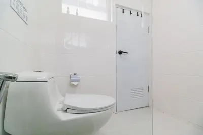 a white bathroom with a toilet and a shower at Huai Khwang Cozy Home Comforts in Bangkok