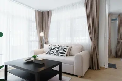 a living room with a white couch and a table at Huai Khwang Cozy Home Comforts in Bangkok
