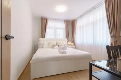 a white bedroom with a white bed and a window at Huai Khwang Cozy Home Comforts in Bangkok