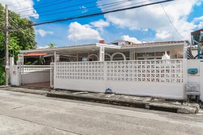a white fence in front of a white house at Huai Khwang Cozy Home Comforts in Bangkok