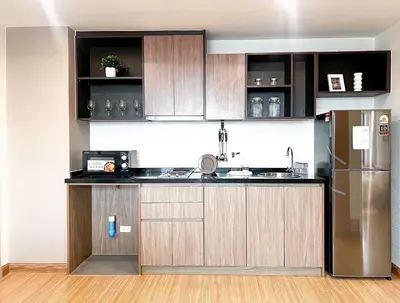 a kitchen with wooden cabinets and a stainless steel refrigerator at The Gallery Bearing in Samut Prakan