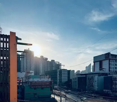 a view of a city with the sun in at Regalohome Bkk in Bangkok