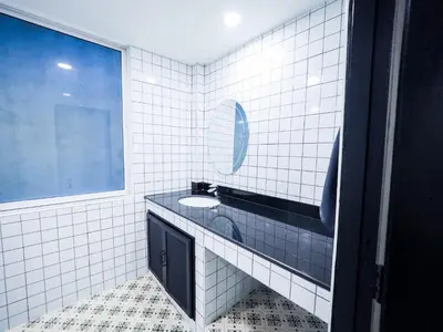 a white tiled bathroom with a sink and a window at Oliver's House KS in Ban Yang