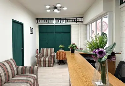 a living room with a table and a green door at Atlas Hostel Khaosan in Bangkok
