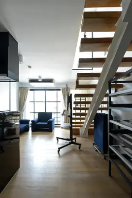 a living room with a staircase and a blue couch at Bangkok Feliz Sukumvit69 in Bangkok