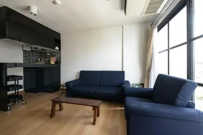 a living room with two blue couches and a table at Bangkok Feliz Sukumvit69 in Bangkok