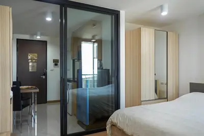 a bedroom with a bed and a sliding glass door at Bangkok Feliz Sukumvit69 in Bangkok