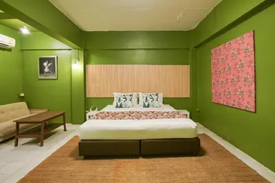 a green bedroom with a bed and a couch at XX GO INN The Grand Palace I โกอินน์ พระบรมมหาราชวัง in Bangkok