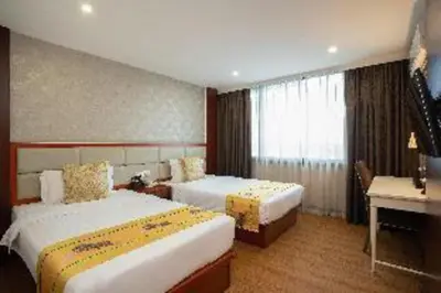 a hotel room with two beds and a desk at Palette The Travellers Hotel Bangkok in Bangkok