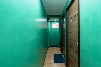 a hallway with a blue wall and a wooden door at GO INN The Giant Swing เสาชิงช้า in Bangkok