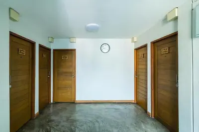 a hallway with wooden doors and a clock on a wall at XX GO INN Khaosan BKK The Grand Palace - โกอินน์ ถนนข้าวสาร in Bang Bua Thong Railway Station