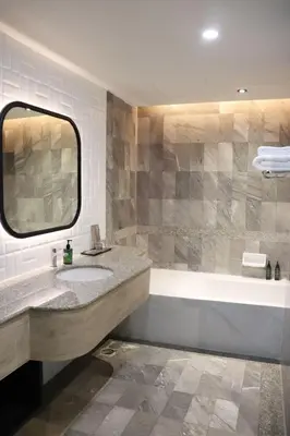 a bathroom with a sink and a tub and a mirror at The Quarter Saphankhwai by UHG in Bangkok