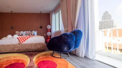 a bedroom with a large blue chair in front of a bed at Retrovibes Sathorn BTS ICONSIAM Asiatique Chao Phraya in Bangkok