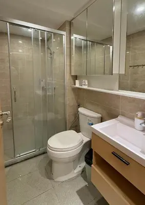 a bathroom with a toilet and a shower and a sink at Regal 40 Srinakarin Apartment in Bangkok