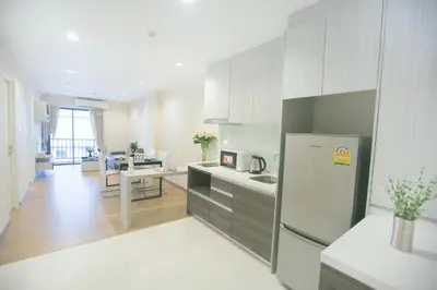 a kitchen with a refrigerator and a living room at Park 19 Hotel in Bangkok