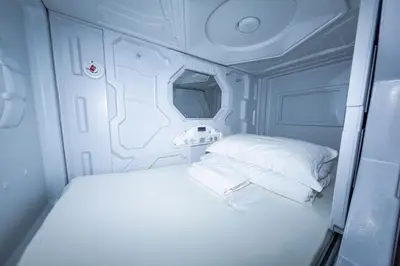 a small room with a bed and two pillows at Kiwi Capsule Hotel in Bangkok