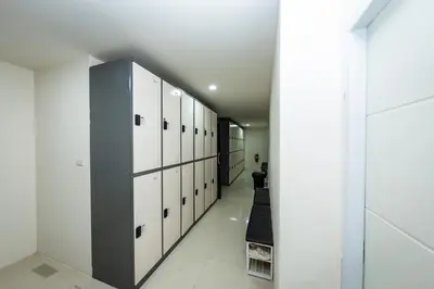a hallway with white lockers in a room at Kiwi Capsule Hotel in Bangkok