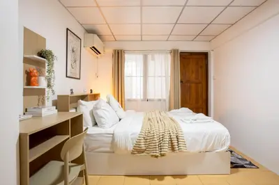 a small bedroom with a bed and a desk at Cosy Lodge MRT Phra Ram 9 in Bangkok