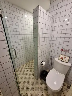 a bathroom with a toilet and a tiled wall at RB9 Oliver's House in Kaset in Ban Yang