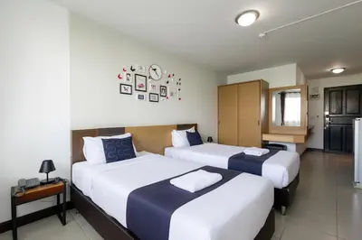 a bedroom with two beds and a kitchen in it at Nature Boutique Hotel Ratchayothin in Bangkok