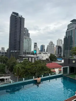 a swimming pool with a city skyline in the background at Spacious Bedroom- 2 mins from Train Station in Bangkok