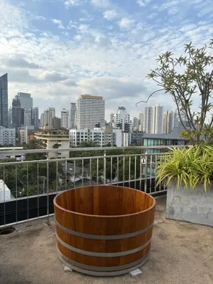 a large wooden barrel on a balcony with a city skyline at Spacious Bedroom- 2 mins from Train Station in Bangkok